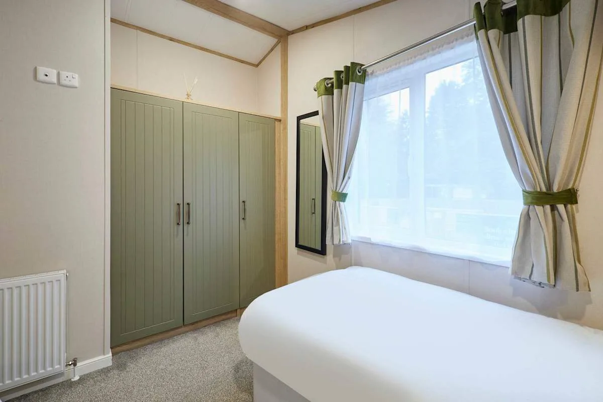 Un dormitorio con cama, armario empotrado y una gran ventana con cortinas.
