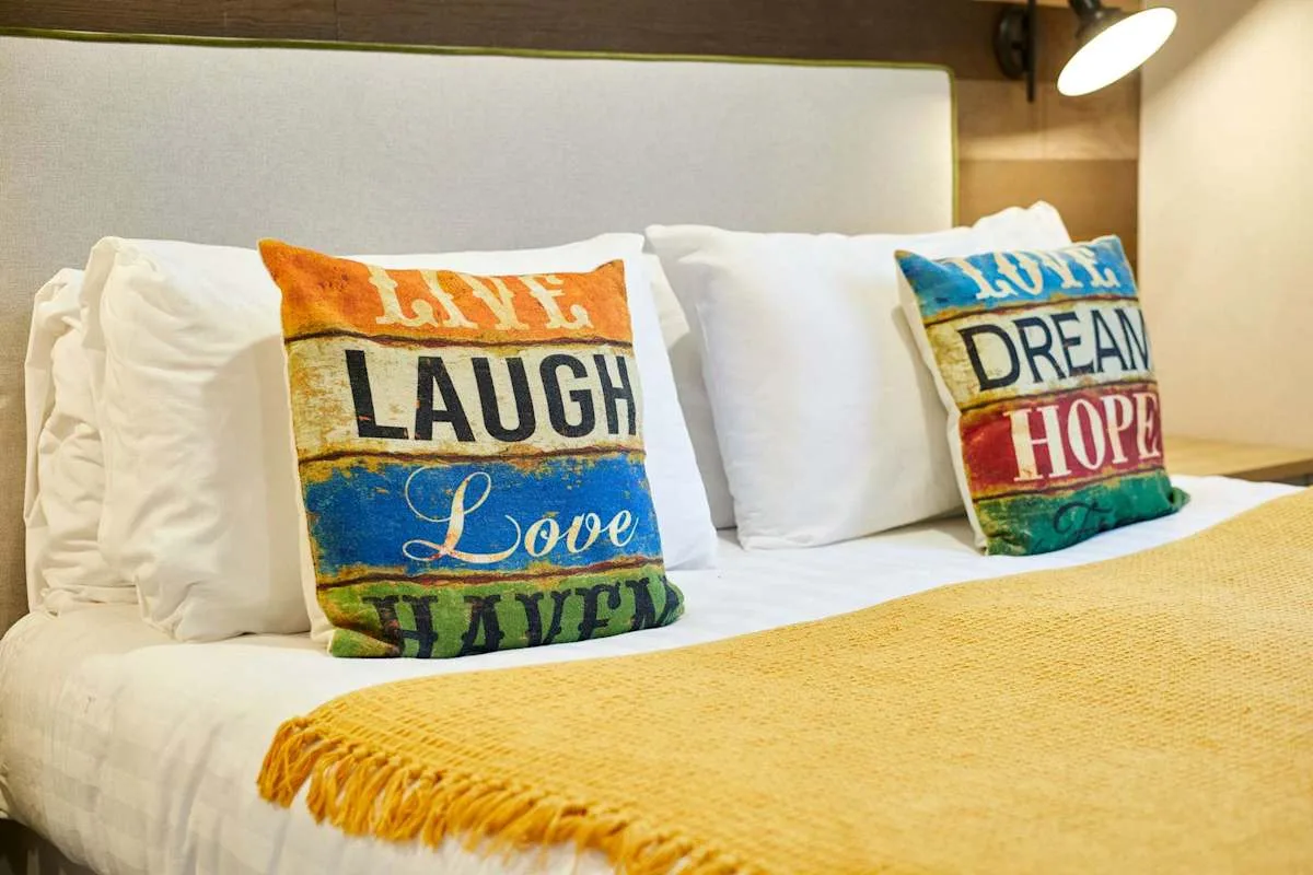 Un dormitorio con una cama bien tendida y cojines decorativos de colores.