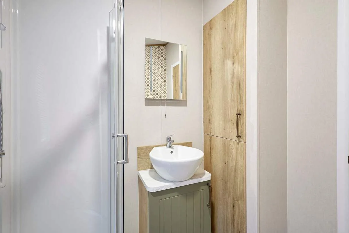 Un baño con un lavabo blanco junto a una puerta de madera.