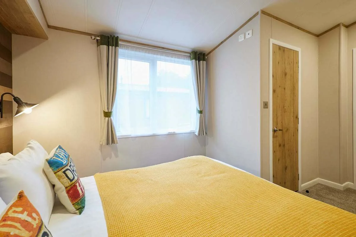 Dormitorio con una cama bajo una ventana luminosa con cortinas.