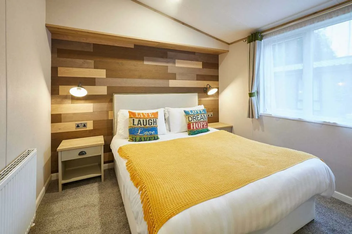 Un dormitorio con una cama doble, una mesita de noche y una ventana con cortinas.