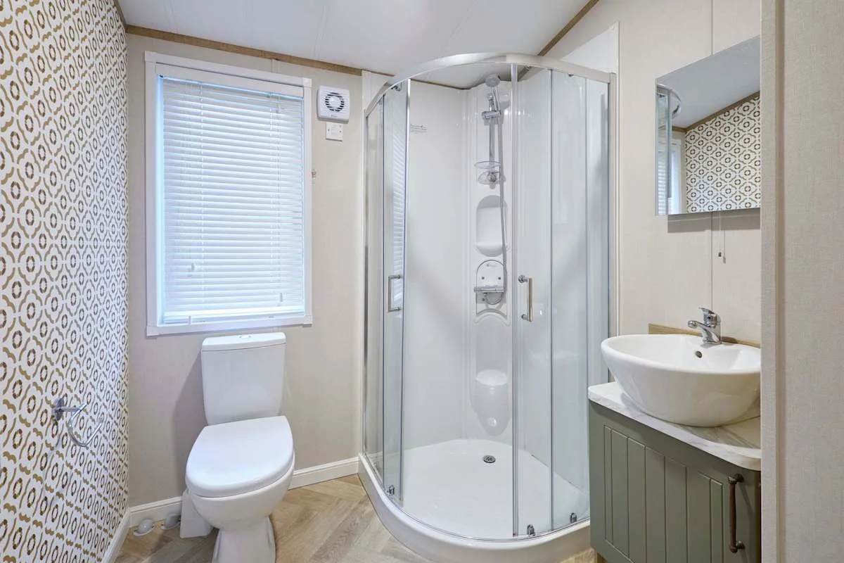 Un baño con ducha curva de cristal, inodoro y lavabo.