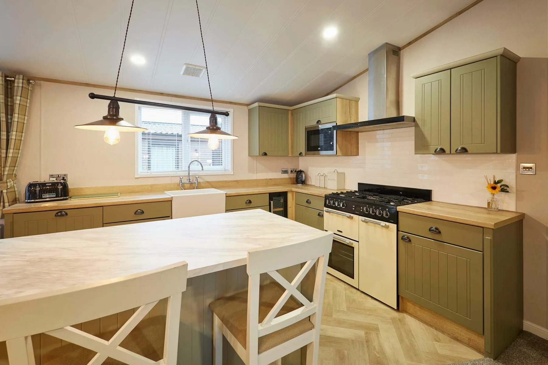 Una cocina con gabinetes verdes, una isla central y una mesa de comedor.