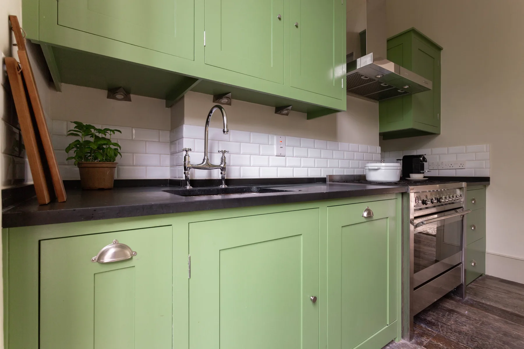 A kitchen with pale green cabinets, a sink, and a stove.
