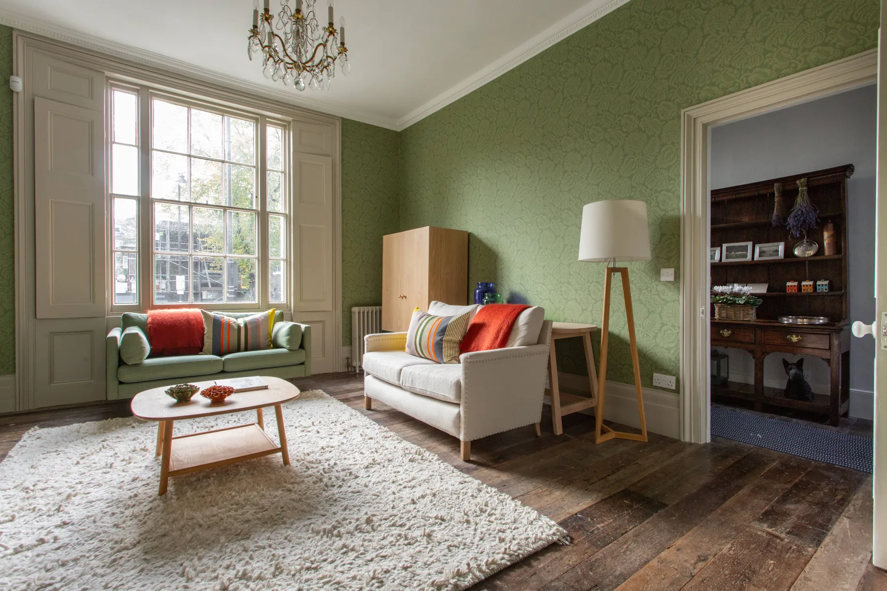 A living room with seating, a large window, and a patterned rug.