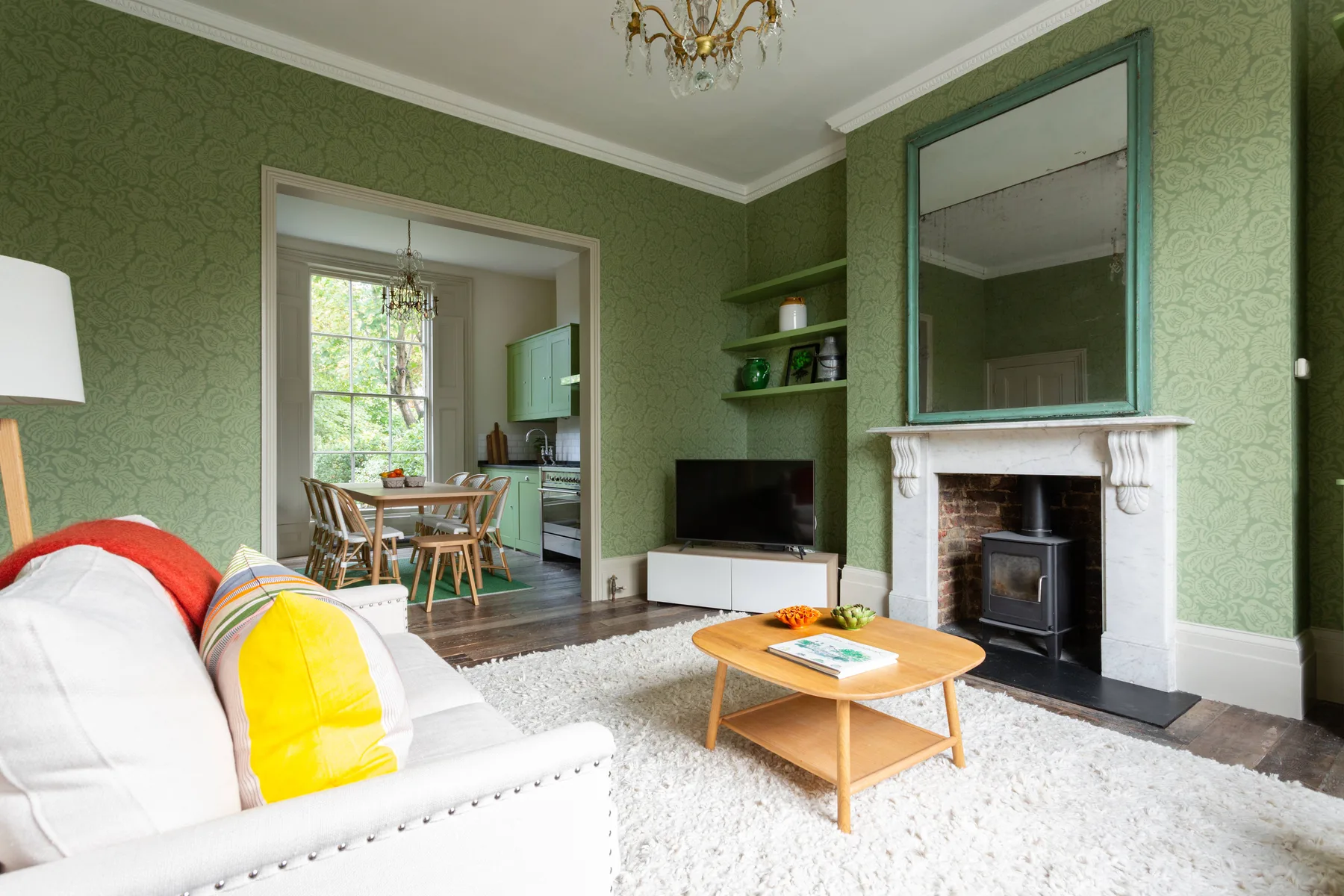 A green living room with a fireplace, television, and seating.