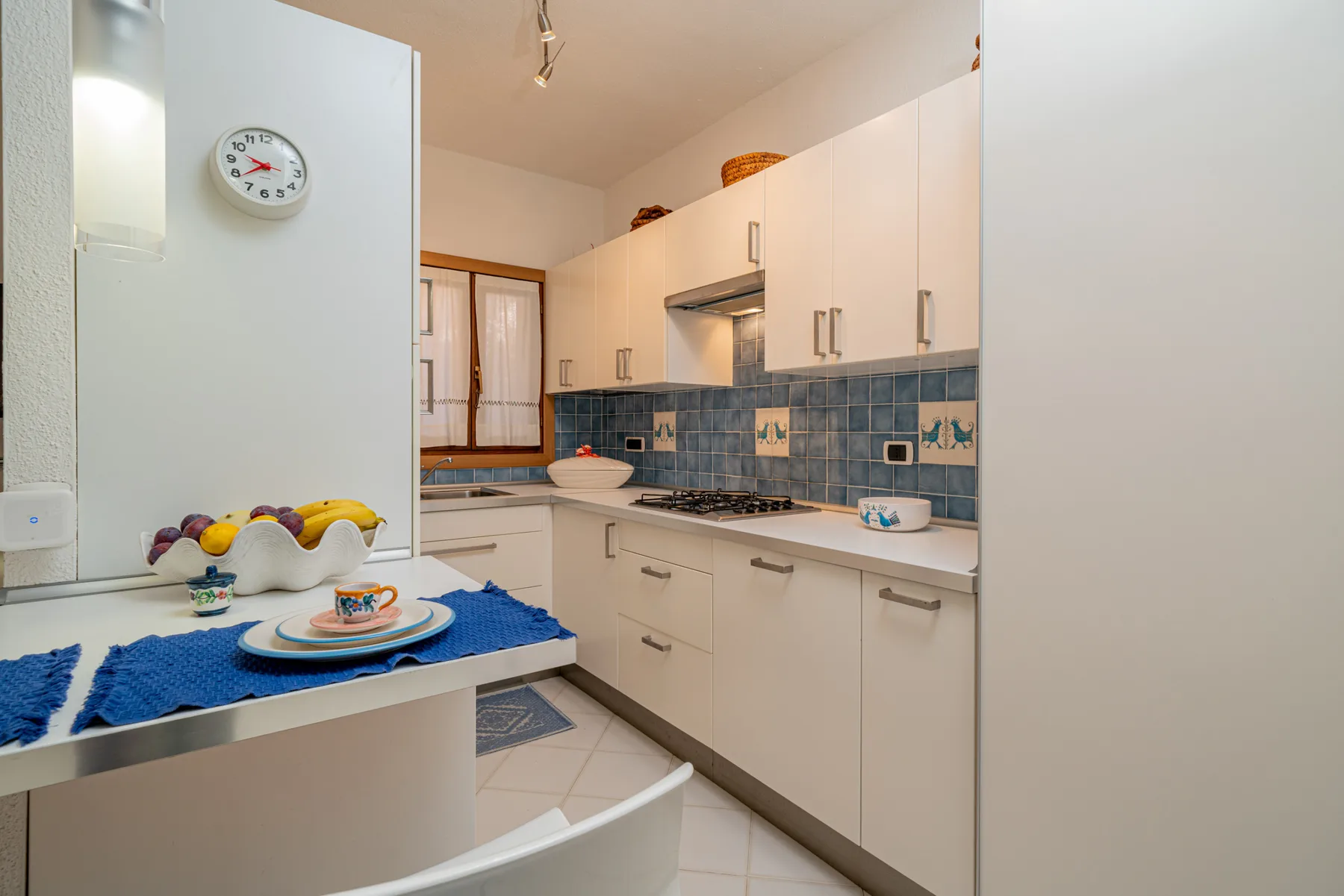 A bright kitchen with white cabinets, a tiled backsplash, and a counter.