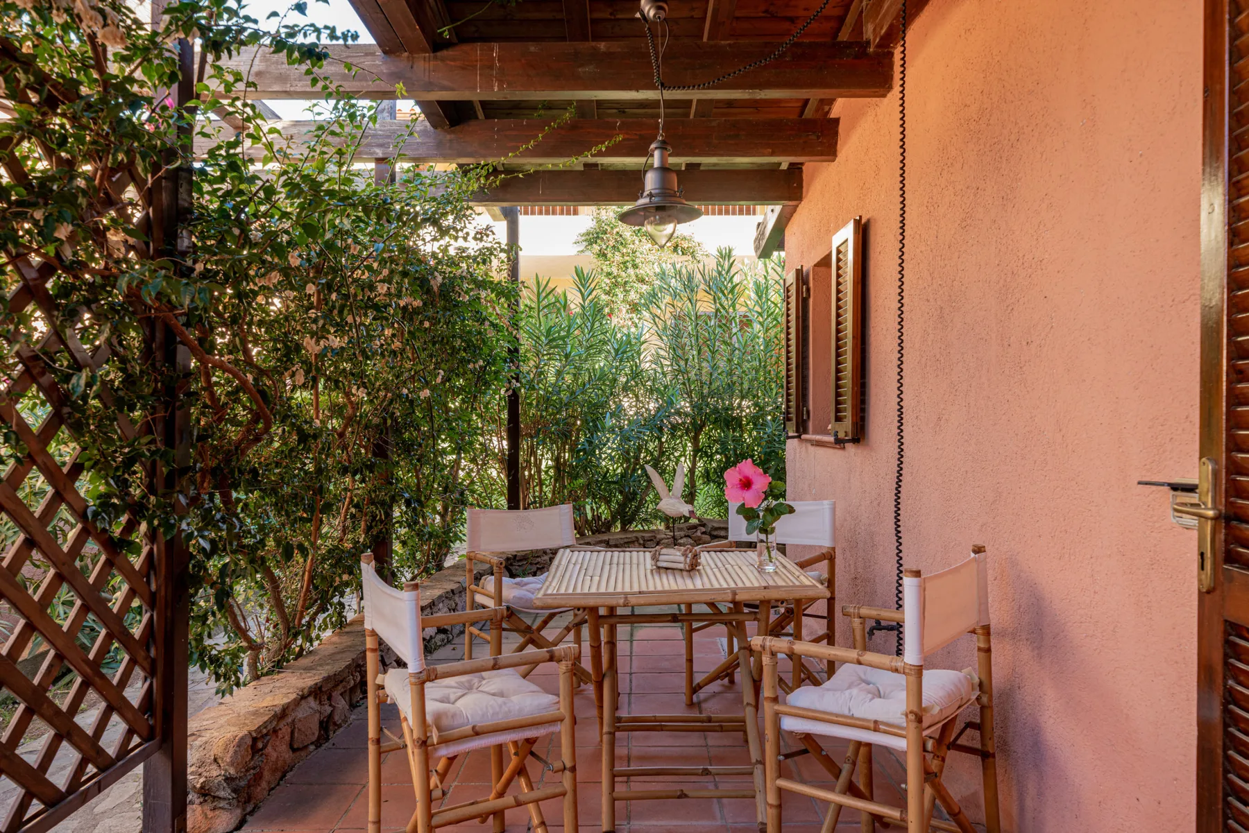 Un patio exterior cubierto con una mesa y sillas está junto a una pared color durazno.