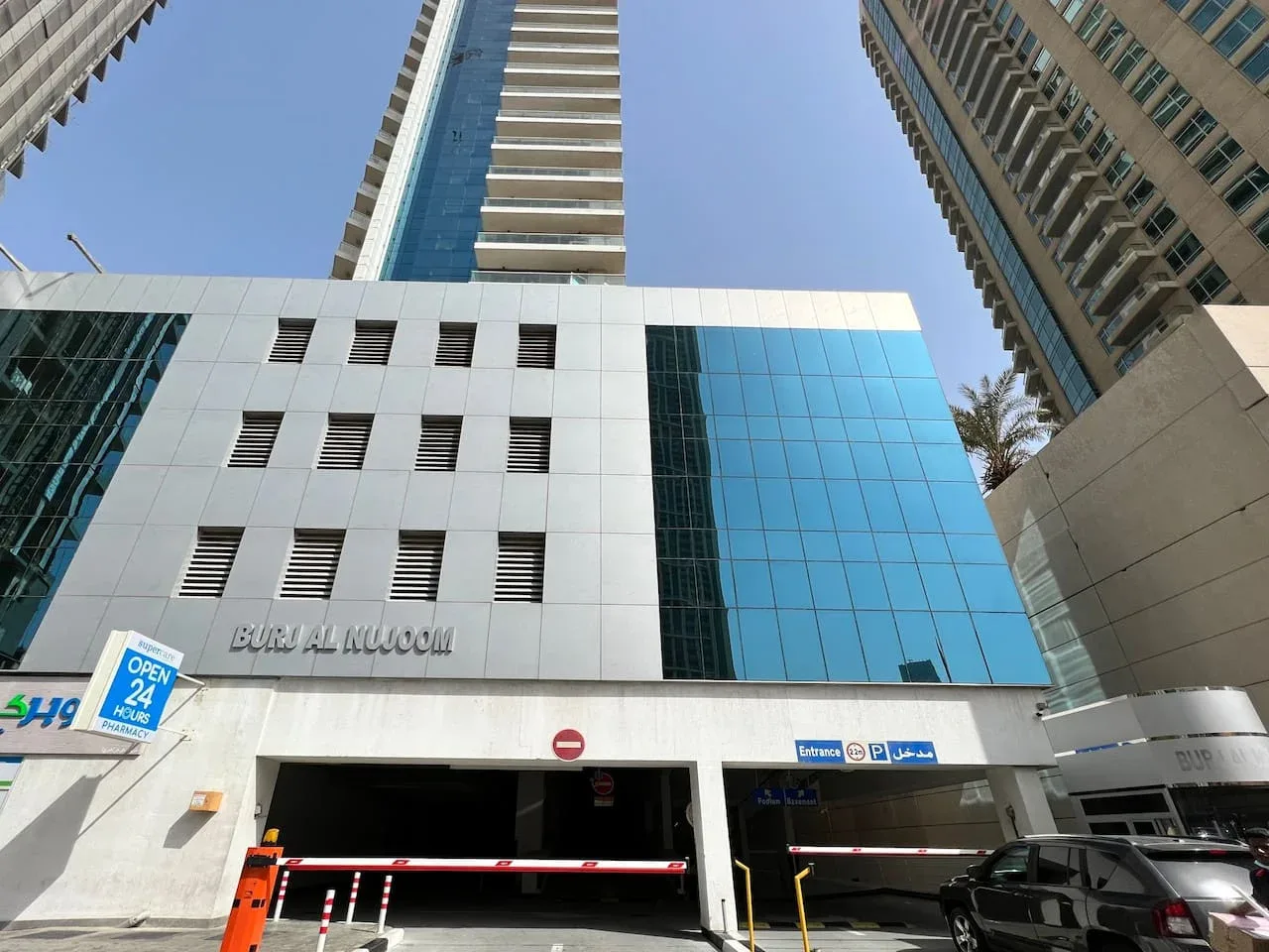 La fachada de un edificio alto moderno con ventanas de vidrio azul y una entrada de estacionamiento.