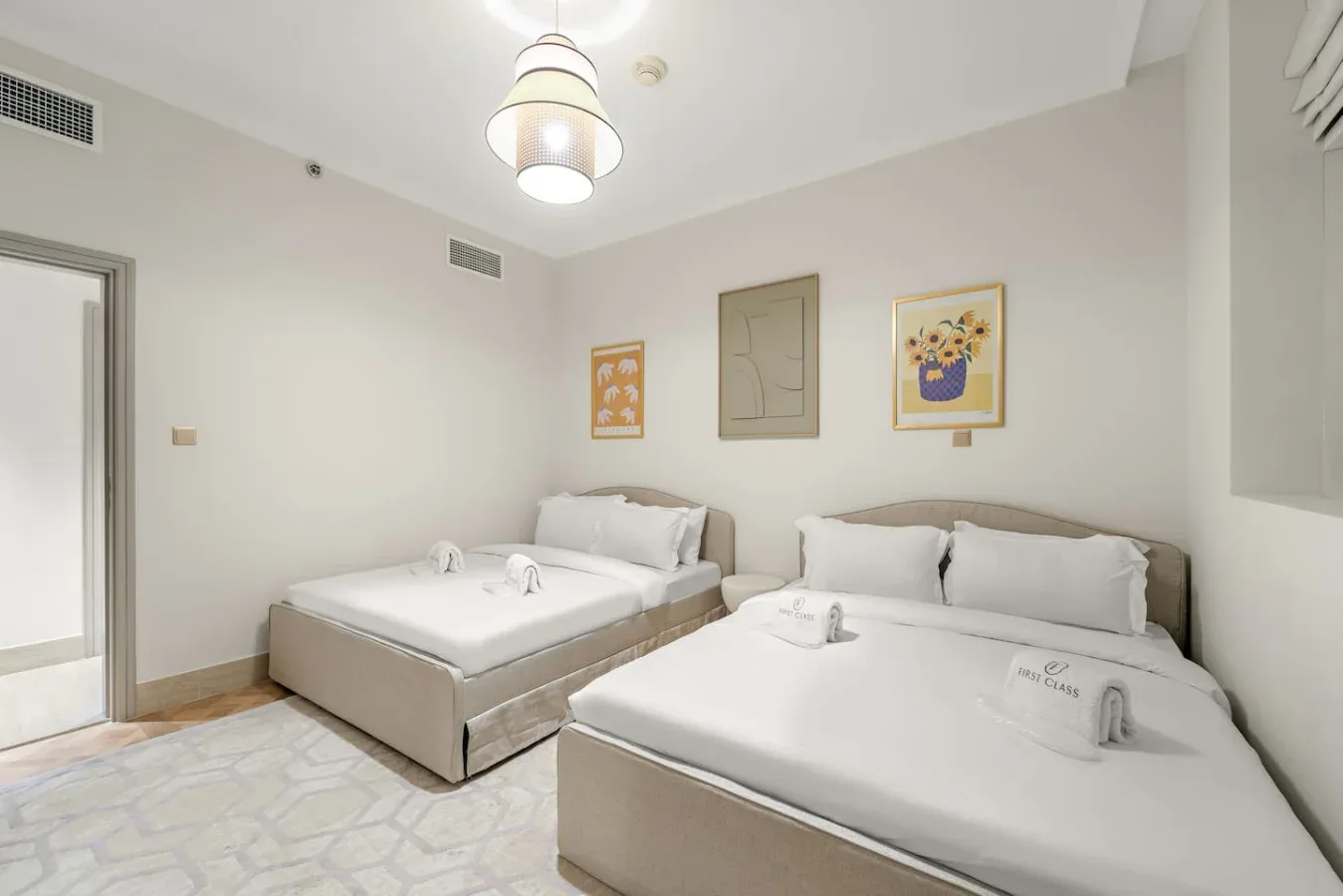 Un dormitorio luminoso con dos camas y cuadros en la pared.