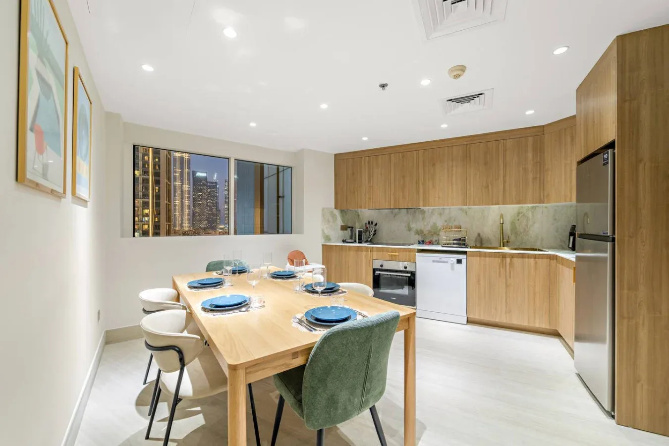 Un comedor da paso a una cocina con gabinetes de madera y una mesa puesta.