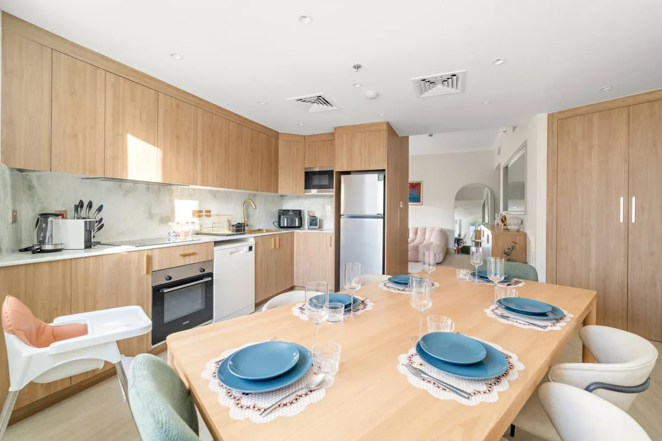Una cocina luminosa con comedor, mesa puesta y electrodomésticos integrados.