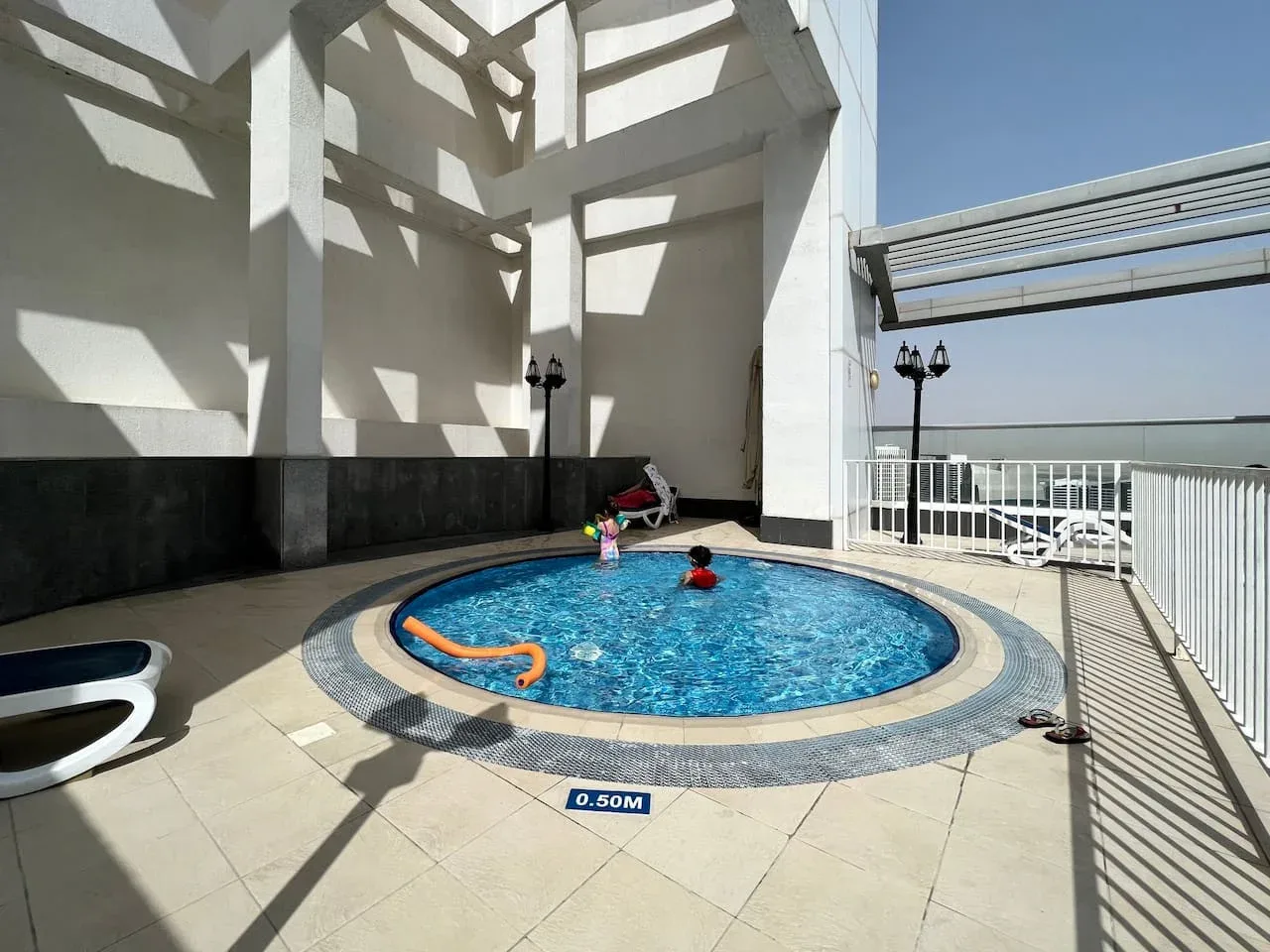 Una piscina en la azotea está junto a una pérgola blanca y una barandilla metálica.