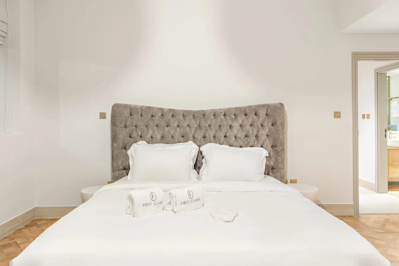 Un dormitorio luminoso con una cama bien hecha y un cabecero tapizado.