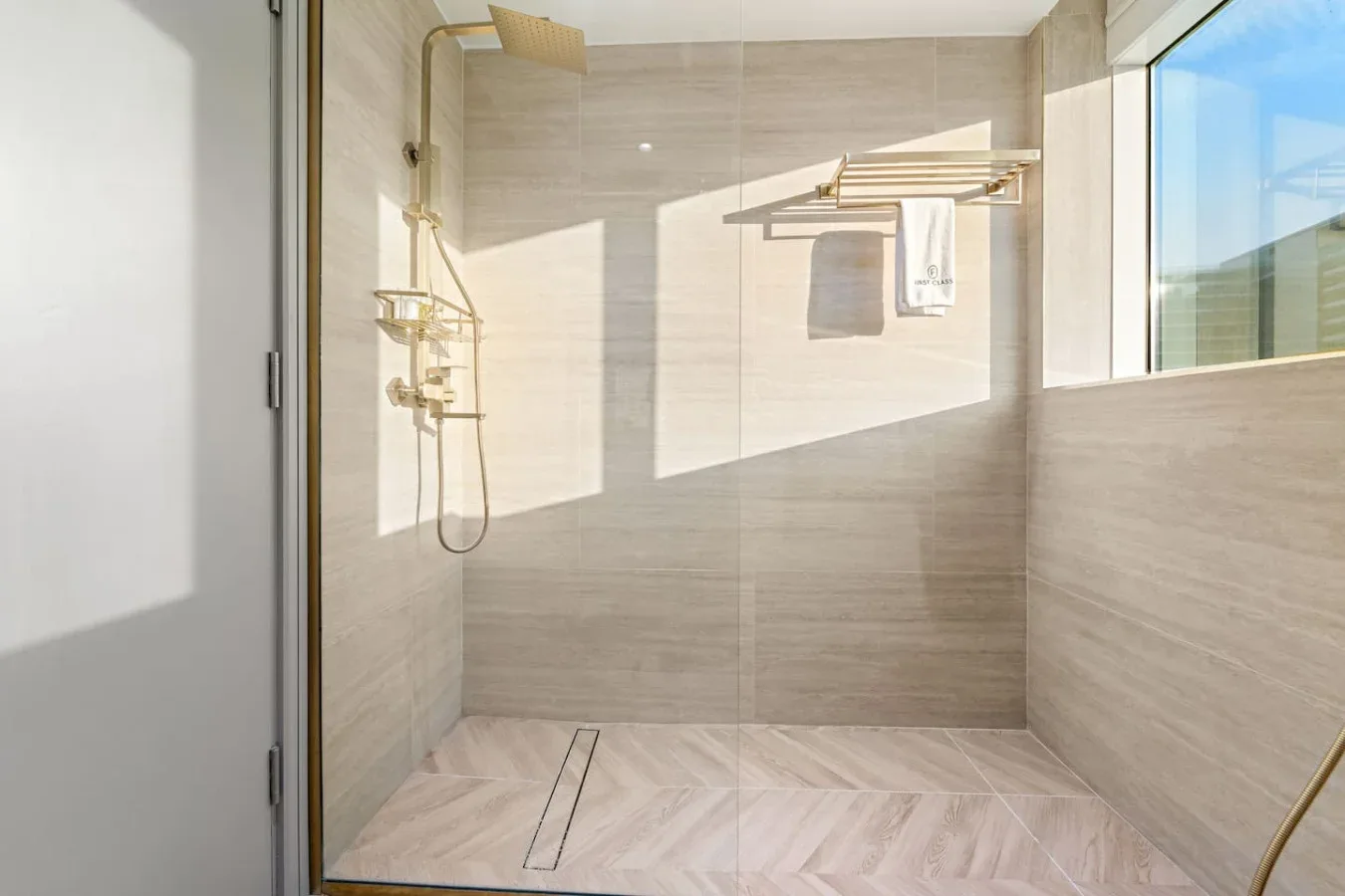 Una zona de ducha luminosa con azulejos, una ventana amplia y accesorios en la pared.