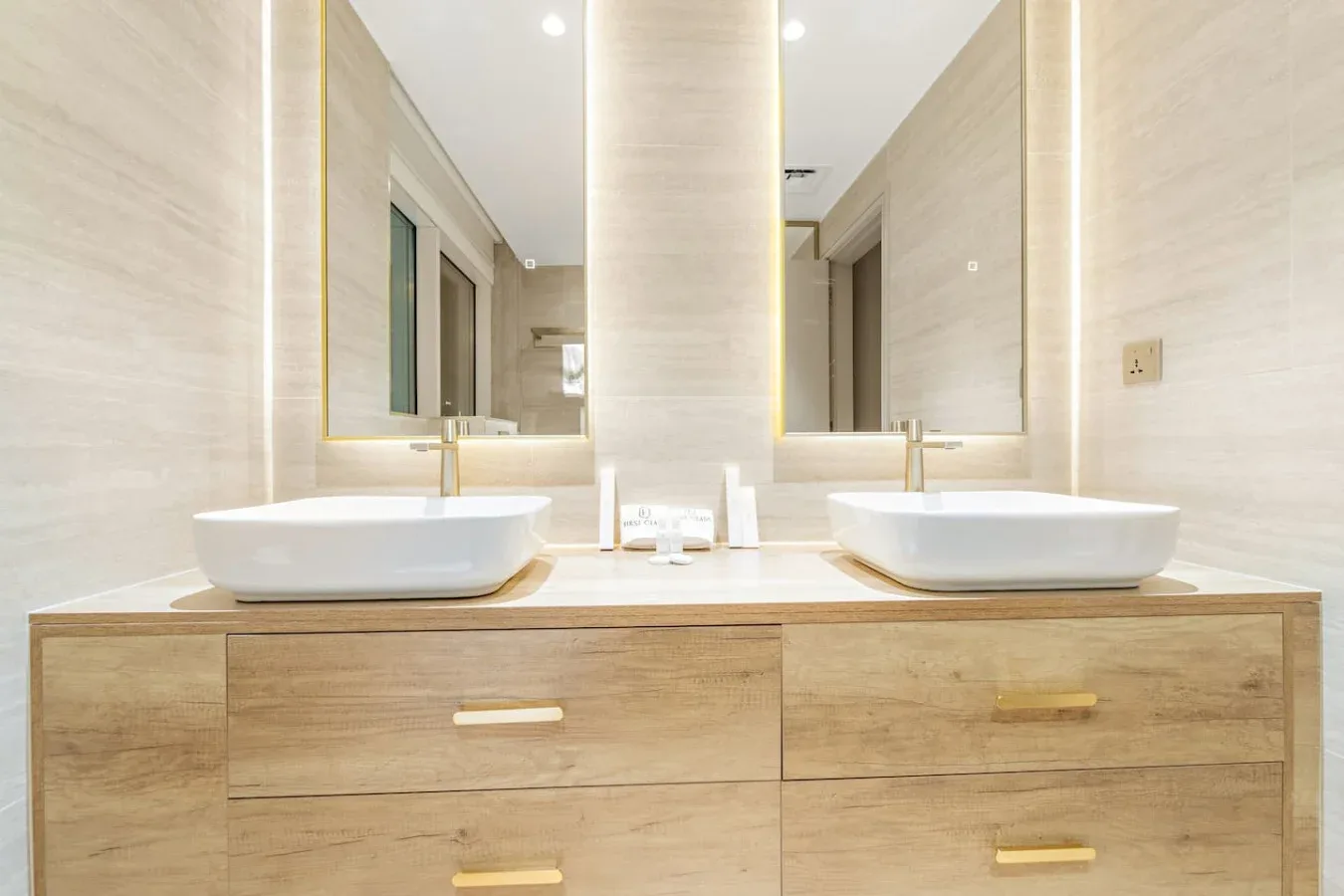 Un tocador de baño luminoso con dos lavabos y espejos grandes.
