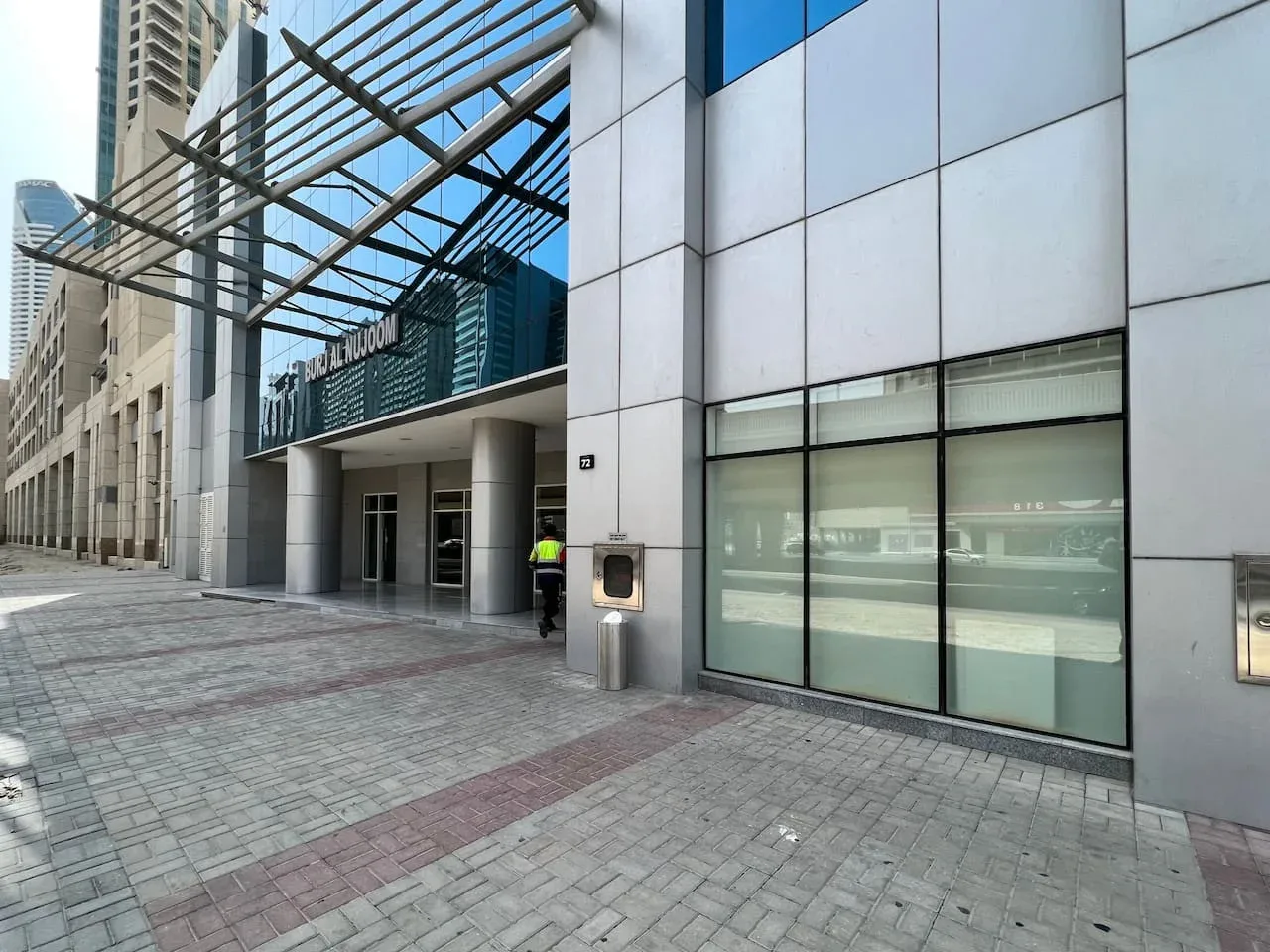 La entrada de un edificio moderno da a una amplia zona peatonal pavimentada.