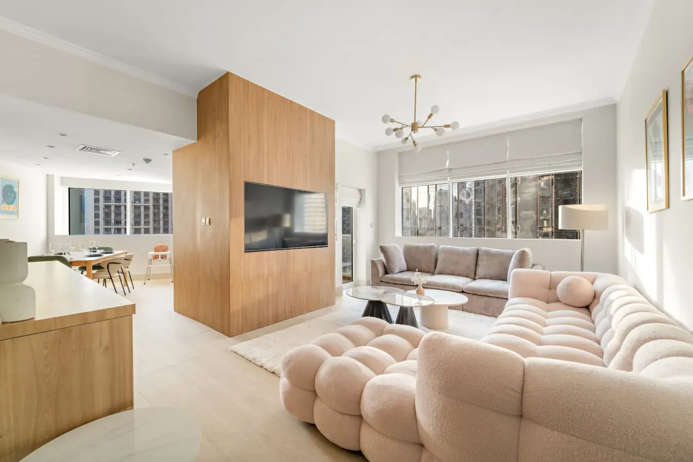 Una sala luminosa con un panel para televisión, asientos y un comedor.