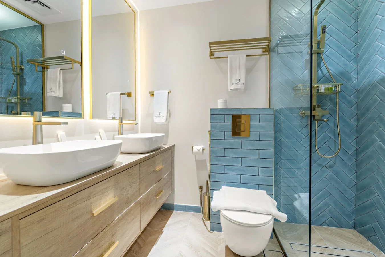 Un baño moderno con lavabo doble y una zona de ducha con azulejos azules.