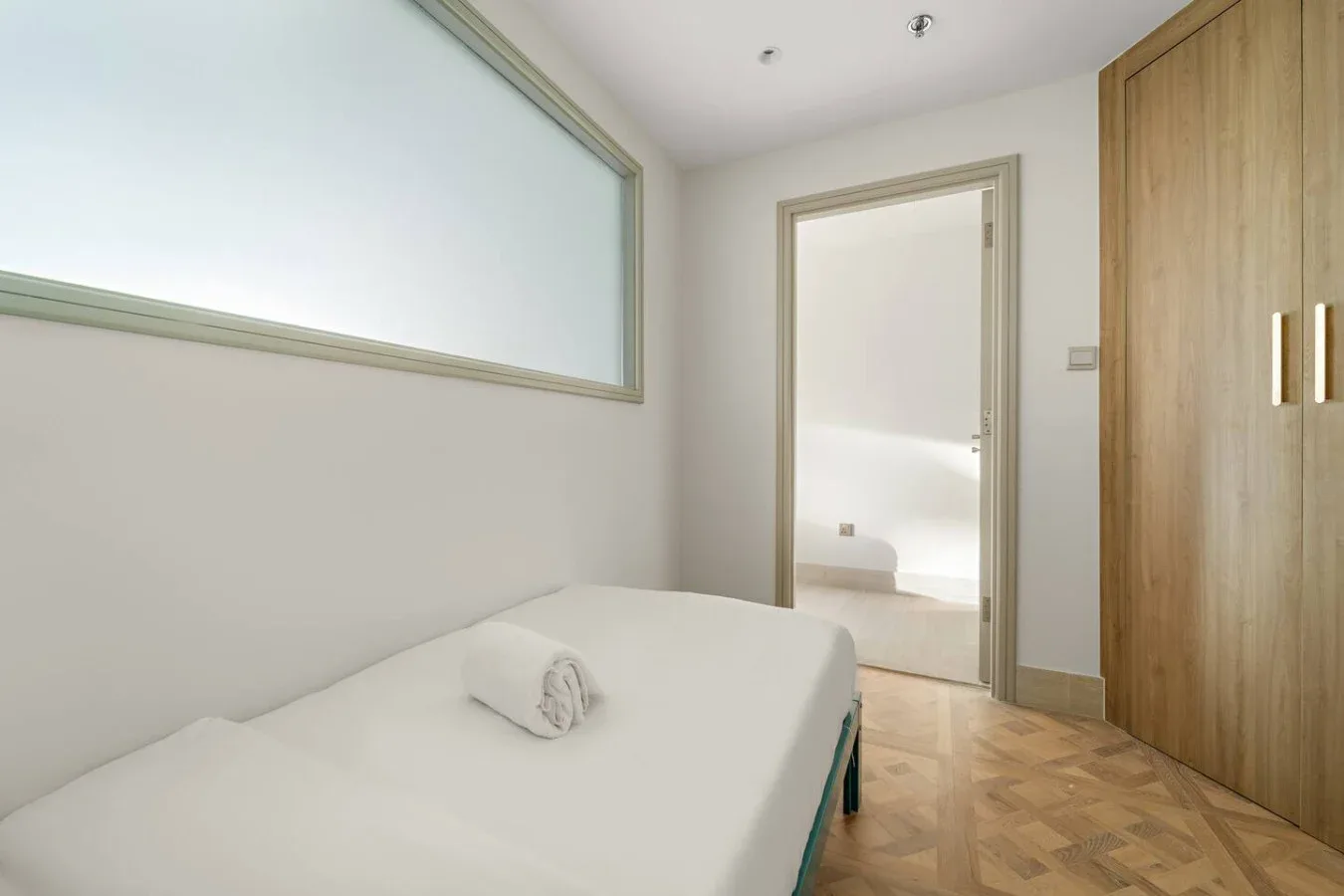 Un dormitorio luminoso con una cama y un armario de madera.