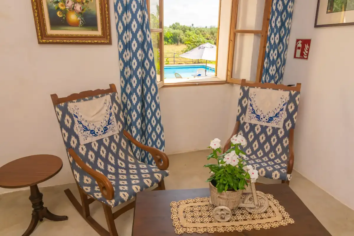 A sitting area with patterned chairs beside a window overlooking a garden.