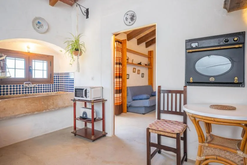 A bright kitchen opens into a sitting area, with a tiled backsplash and built-in oven.
