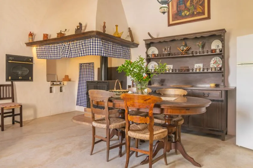 A dining room with a wooden table, chairs, and a large display cabinet.