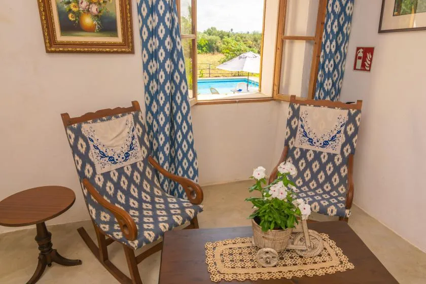 A sitting room with patterned armchairs and a window overlooking greenery.