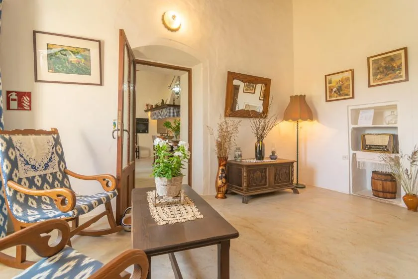 A warmly lit living room with patterned seating, a coffee table, and framed pictures.