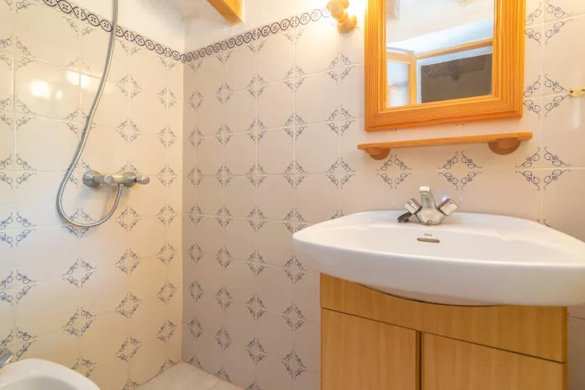 A tiled bathroom with a sink and wall-mounted mirror.