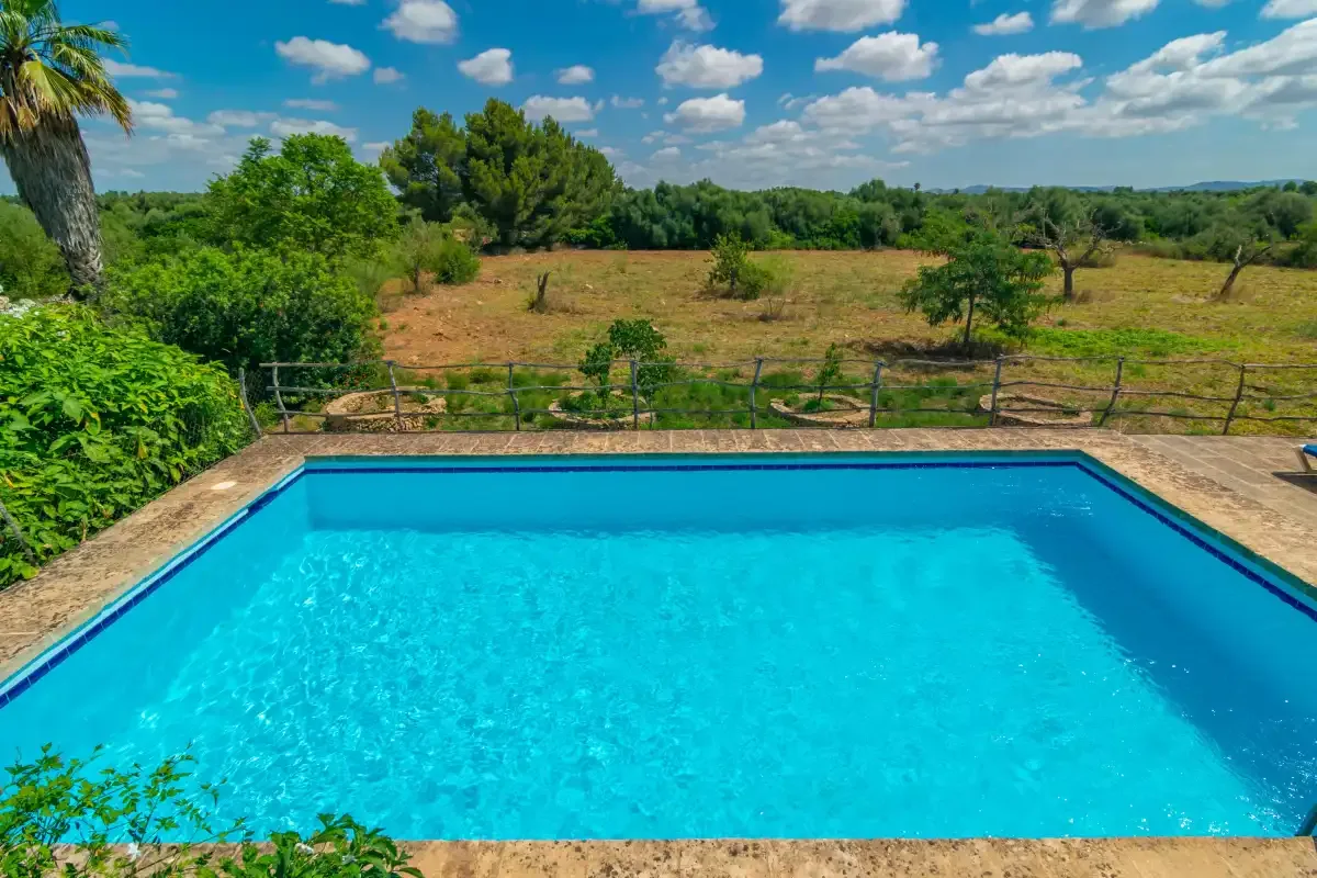 A swimming pool overlooks a green, open landscape.