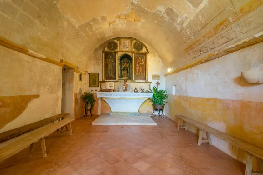 A small chapel with a decorated altar at the far end and benches along the walls.