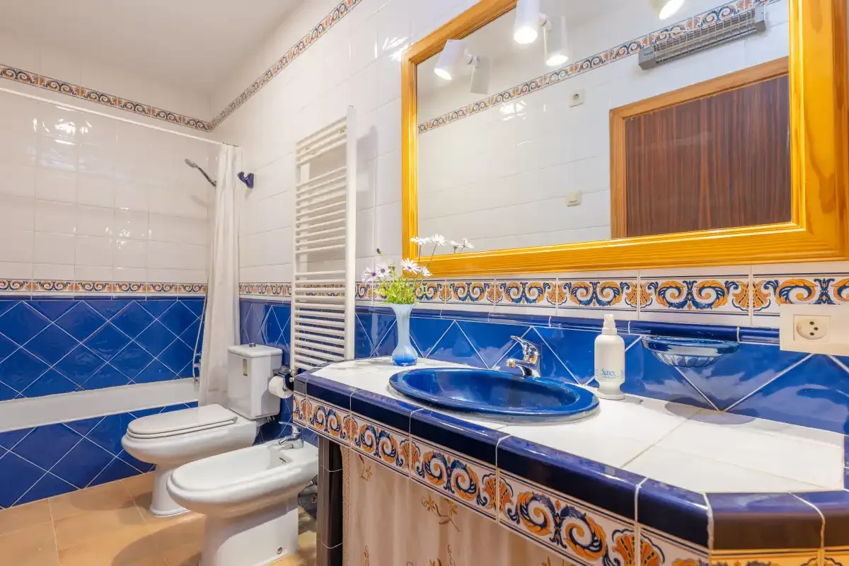 A tiled bathroom with a blue sink and a toilet.