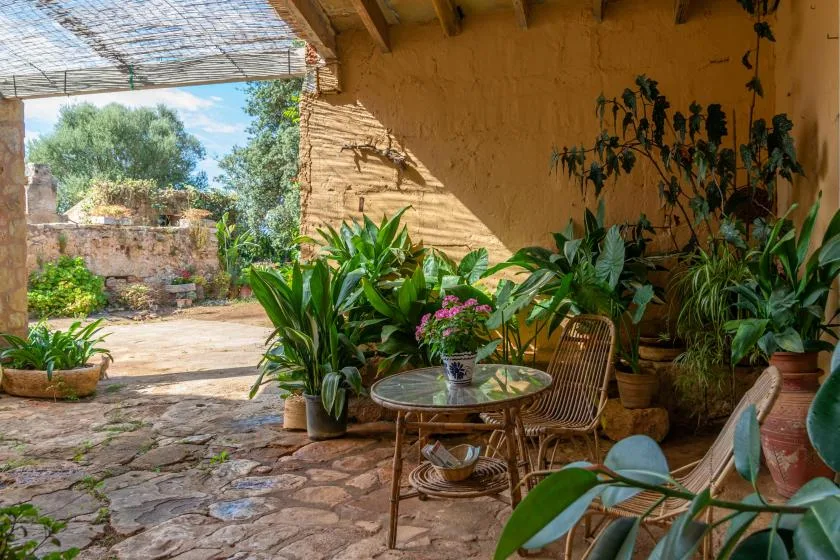A plant-filled outdoor patio with seating and a stone-paved floor.