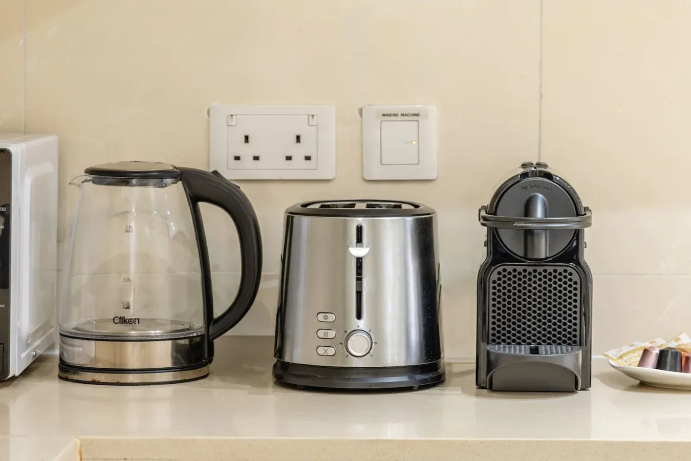 Una encimera de cocina con un hervidor, una tostadora y una cafetera.