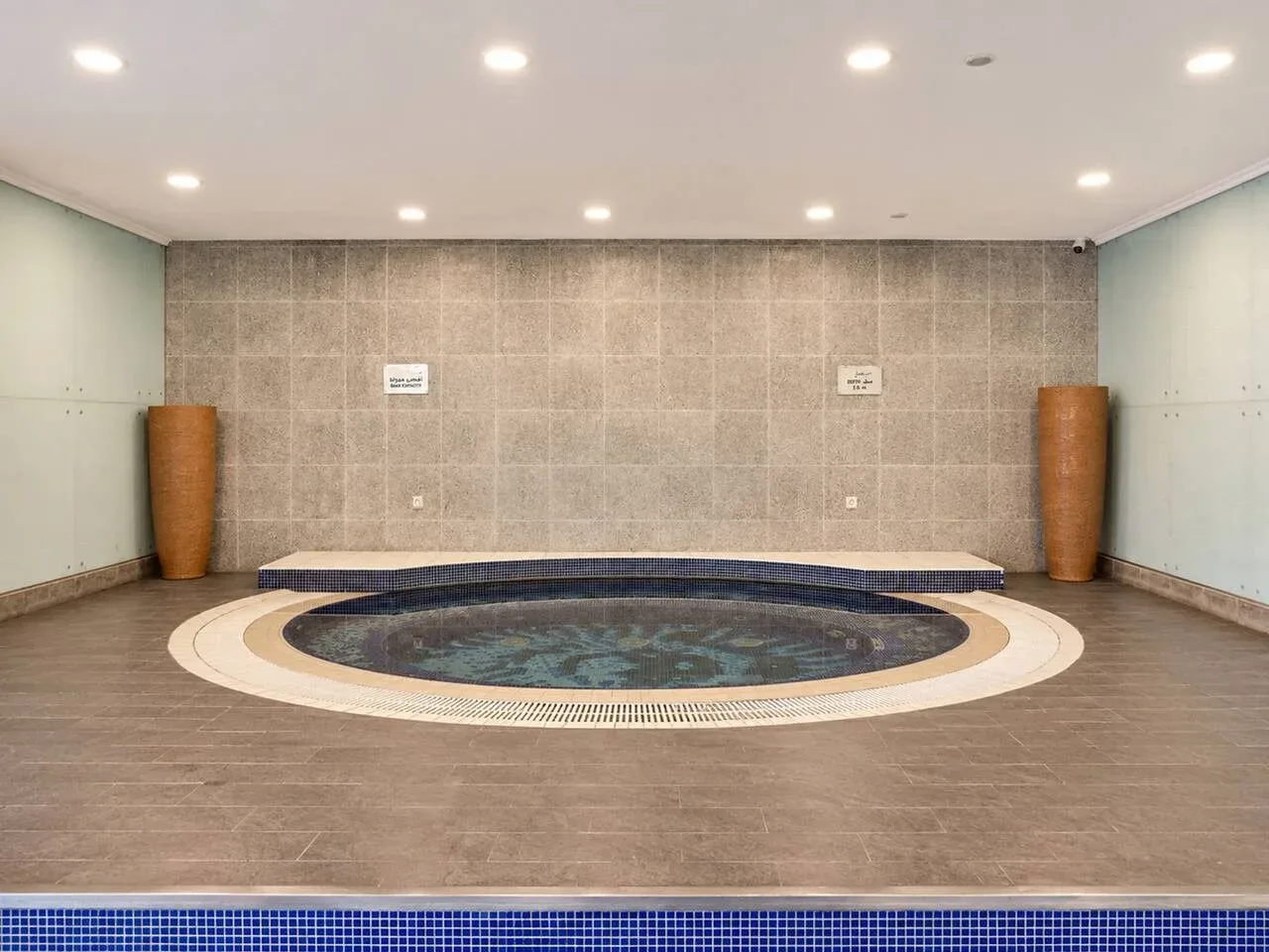Una piscina de spa interior está en una sala alicatada con una pileta circular.