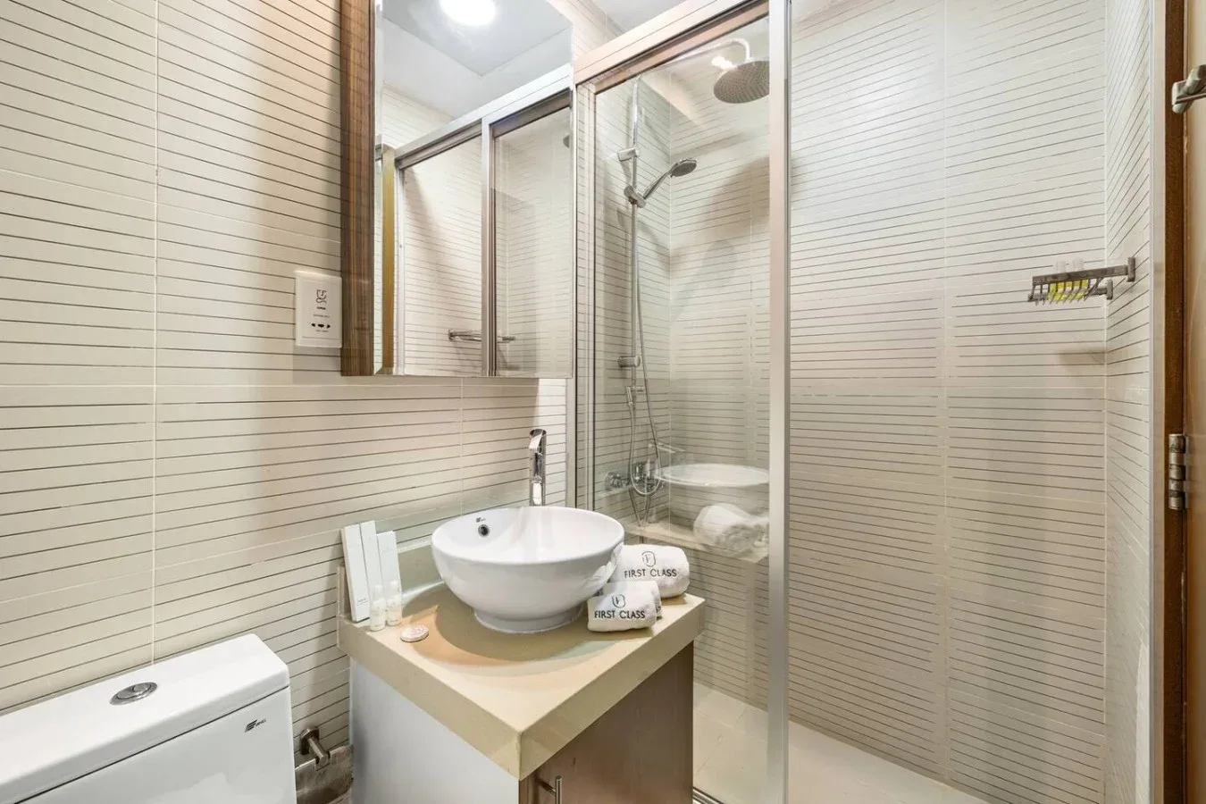 Un baño luminoso con lavabo sobre encimera y ducha con mampara de vidrio.