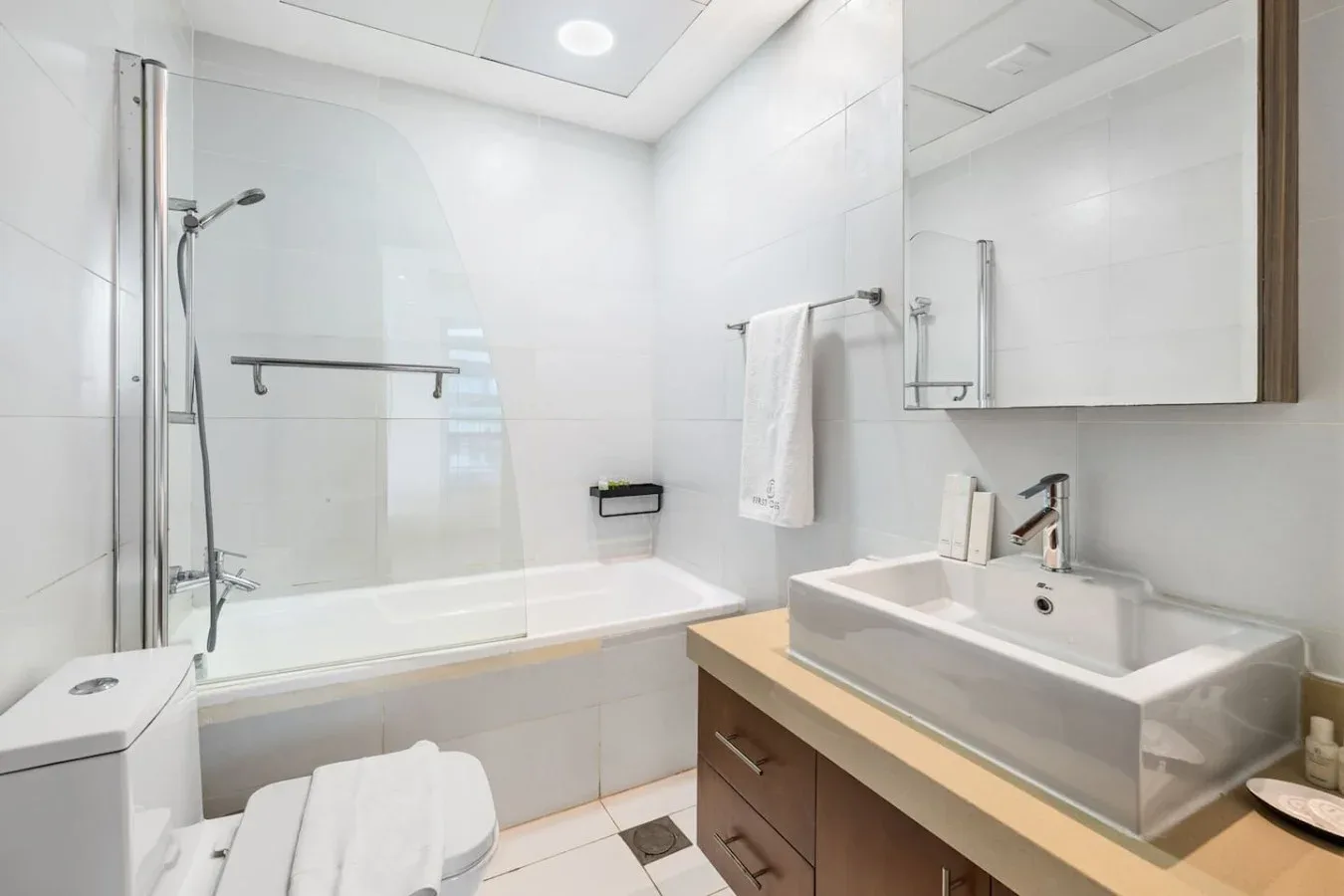 Un baño luminoso con bañera, ducha y lavabo bajo un espejo grande.