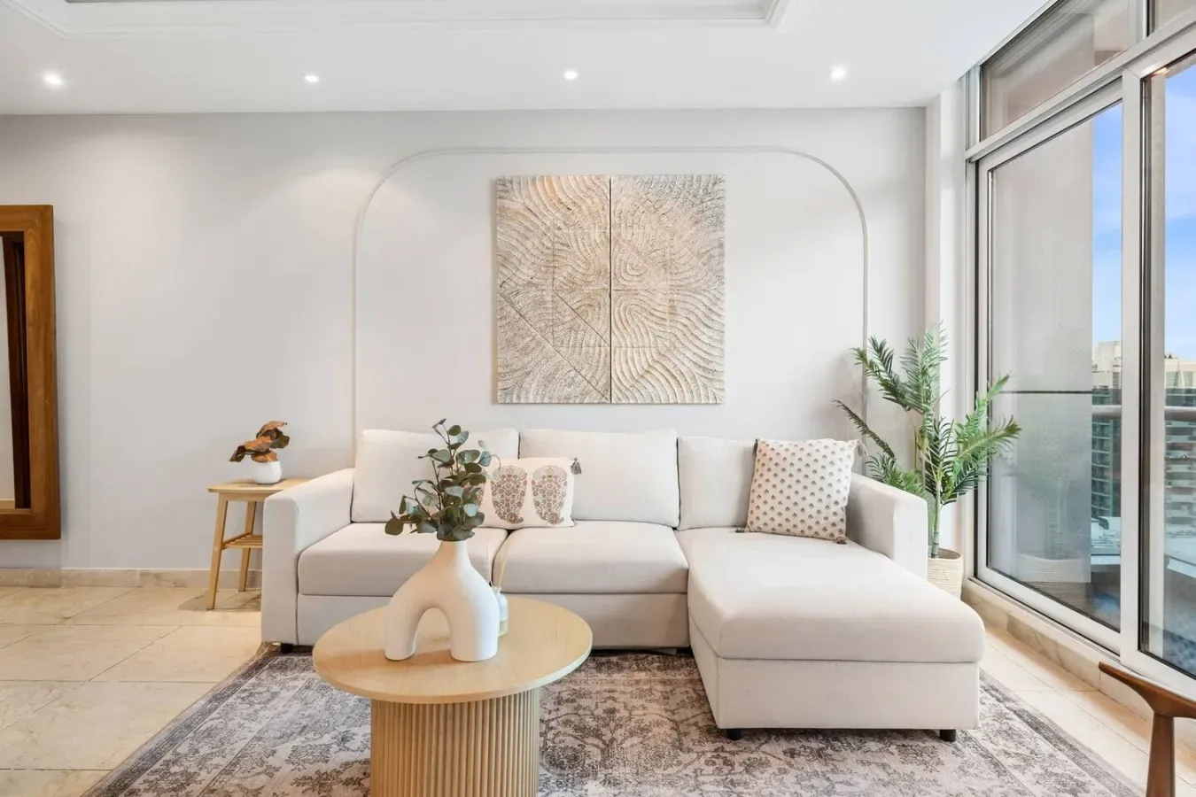 Una sala luminosa con asientos, una mesa de centro y grandes ventanas.