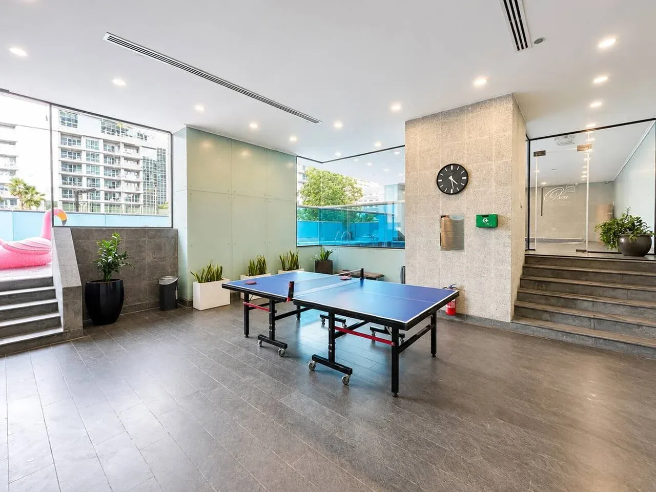 Una luminosa zona recreativa interior cuenta con una mesa de ping-pong junto a grandes ventanales.