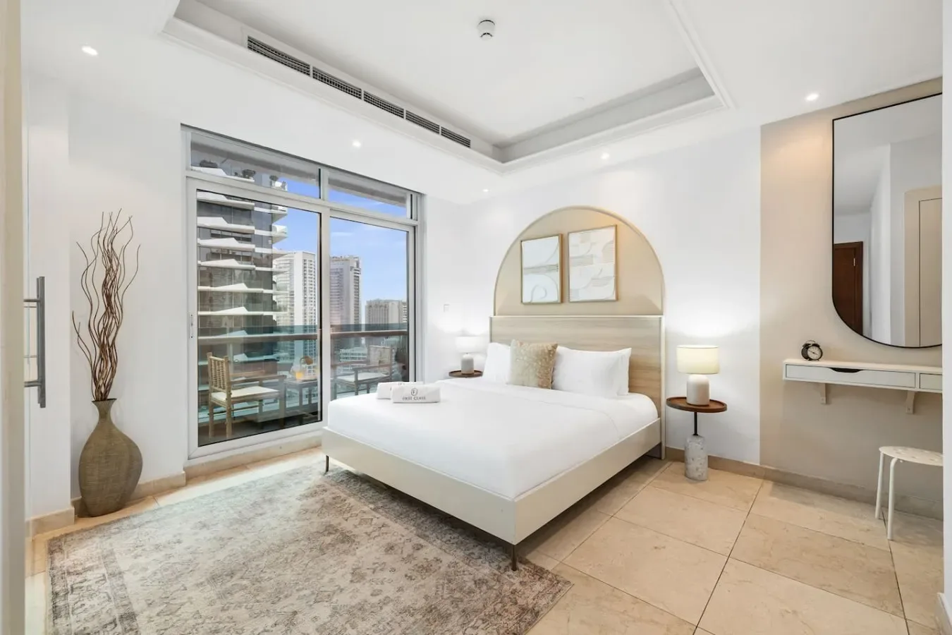 A bright bedroom with a neatly made bed and large windows.