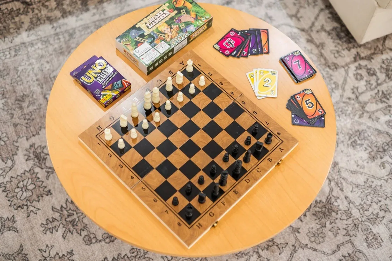 Una mesa redonda de madera tiene un tablero de ajedrez y varios juegos de cartas.