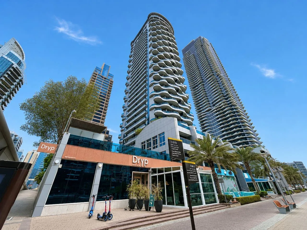 Escena urbana con edificios modernos altos y comercios a nivel de calle.