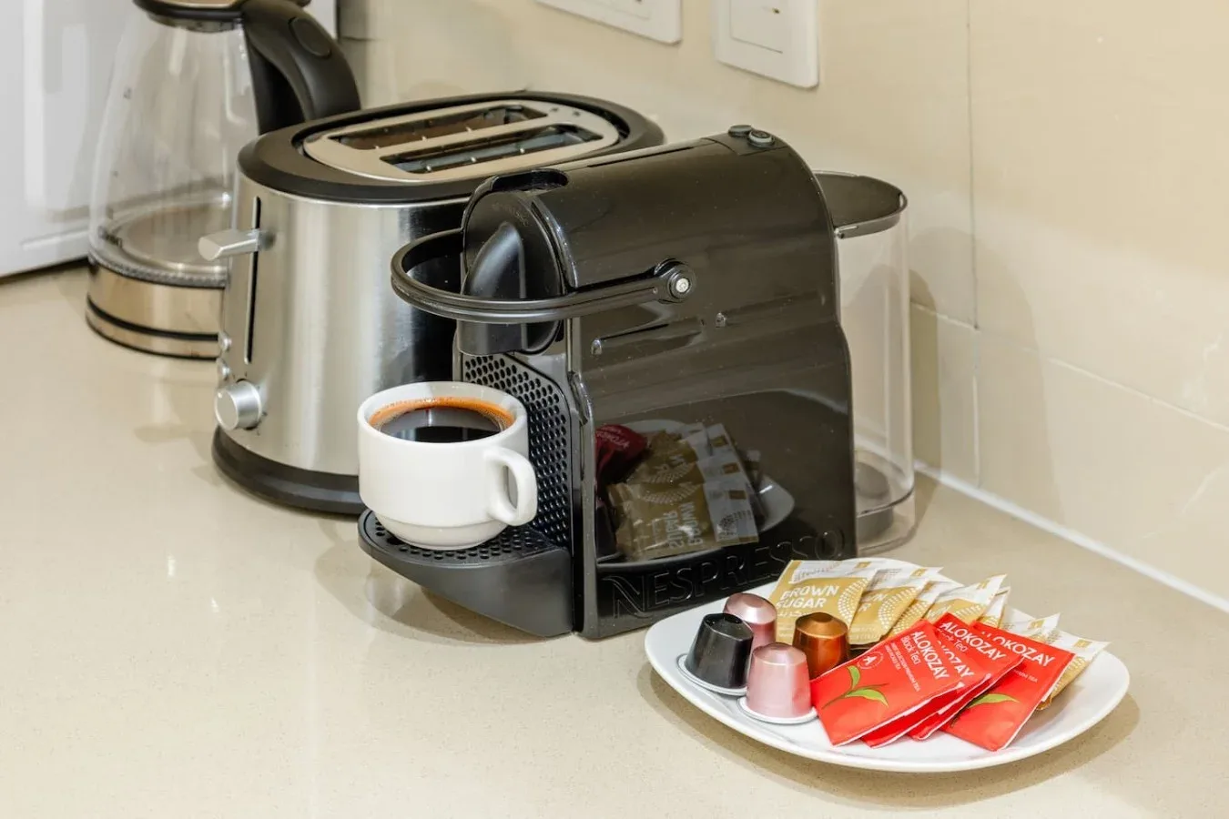 Una encimera de cocina con una cafetera, una taza y artículos para preparar café.
