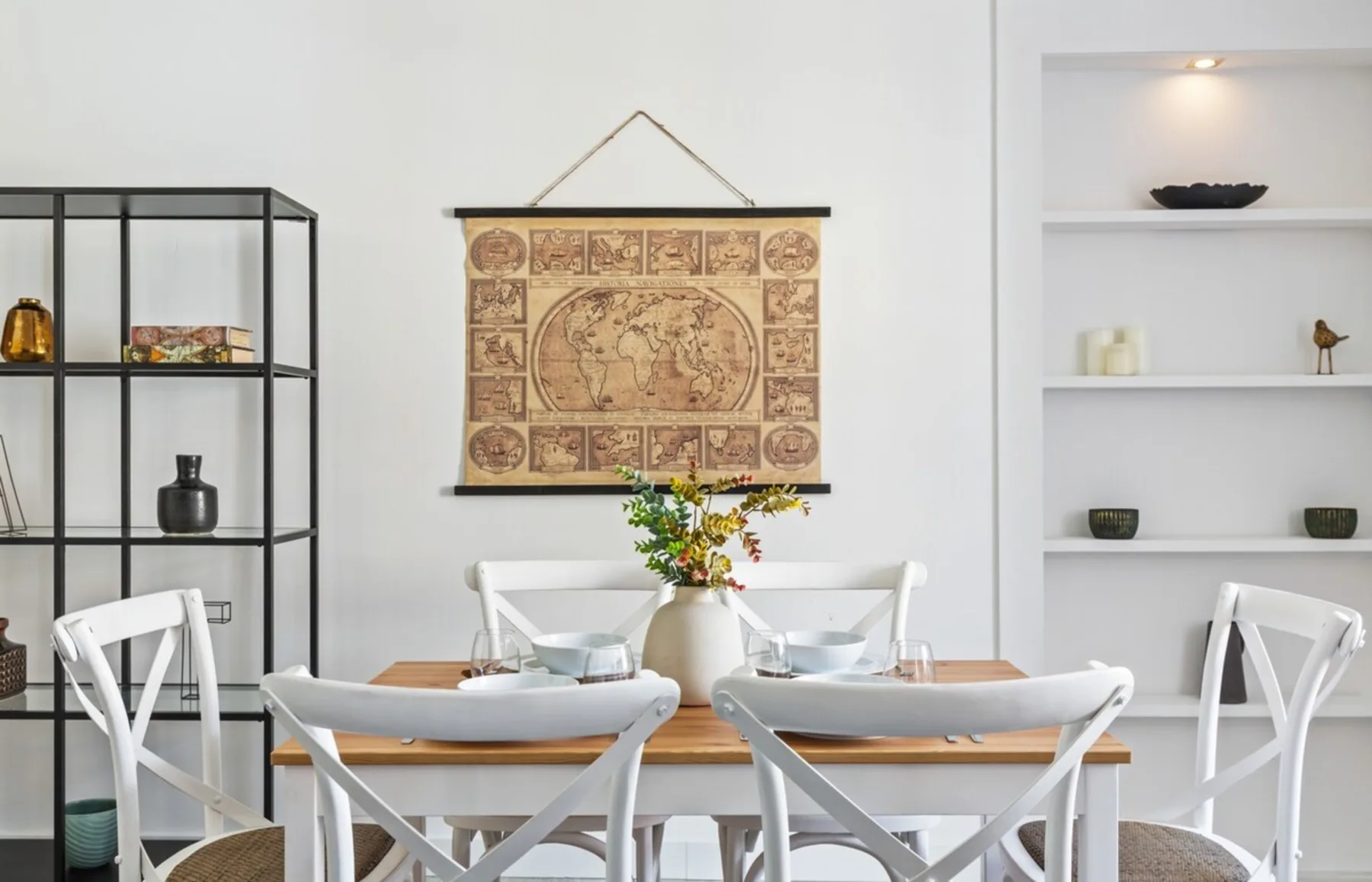 Dining area with a wooden table, white seating, and wall art.