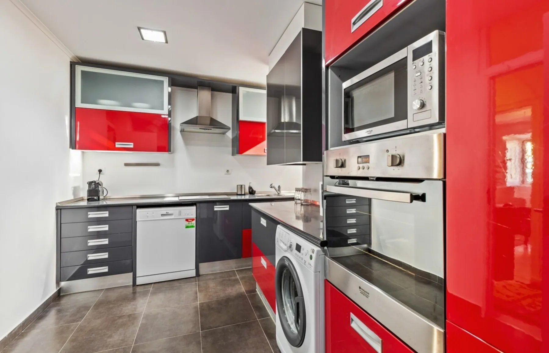 A modern kitchen with red cabinets and built-in appliances.
