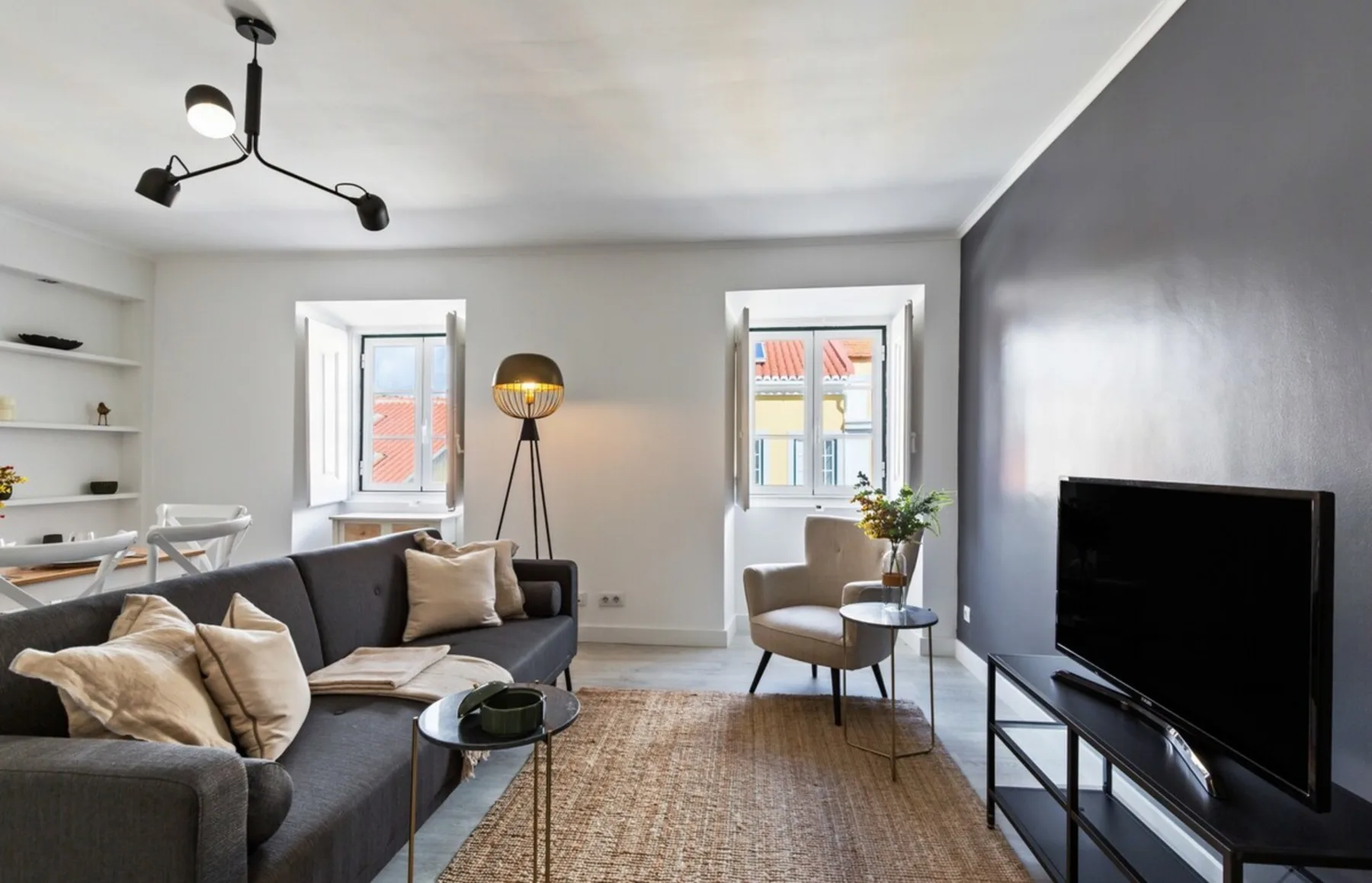 A living room with seating, a television, and windows.