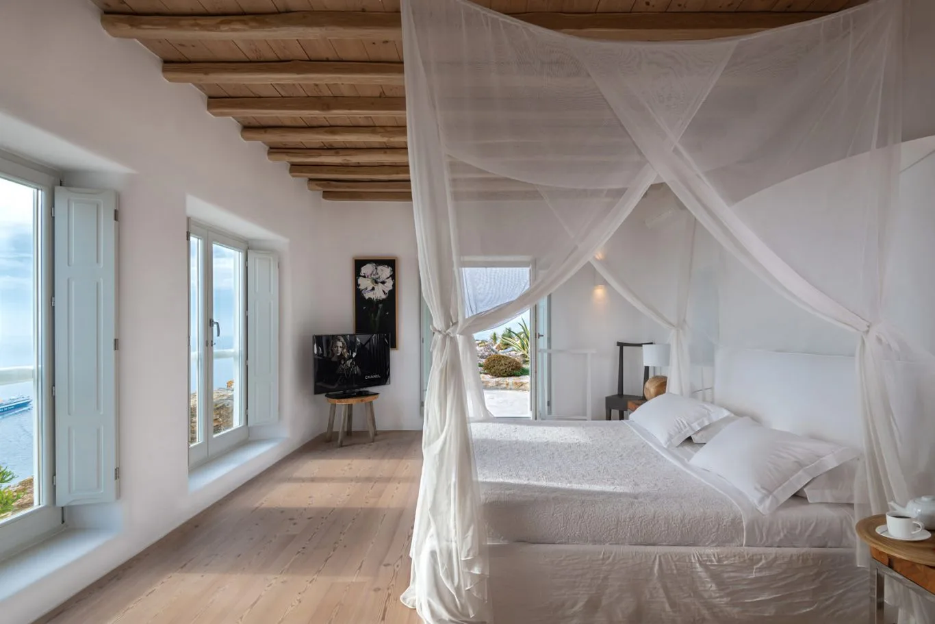 A bedroom with a white bed beneath a draped canopy.