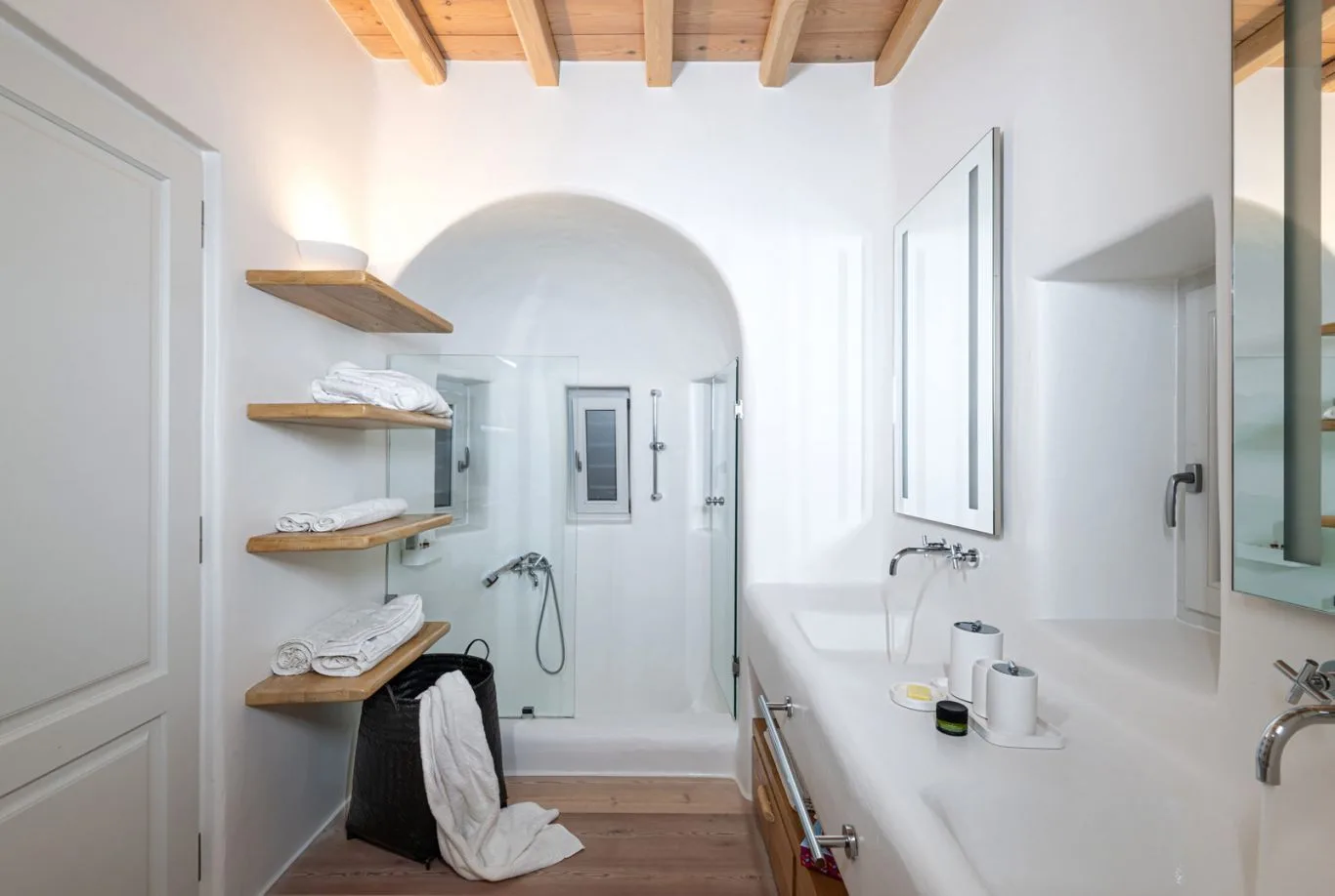 A bright bathroom with a bathtub, sink, and open wooden shelves.