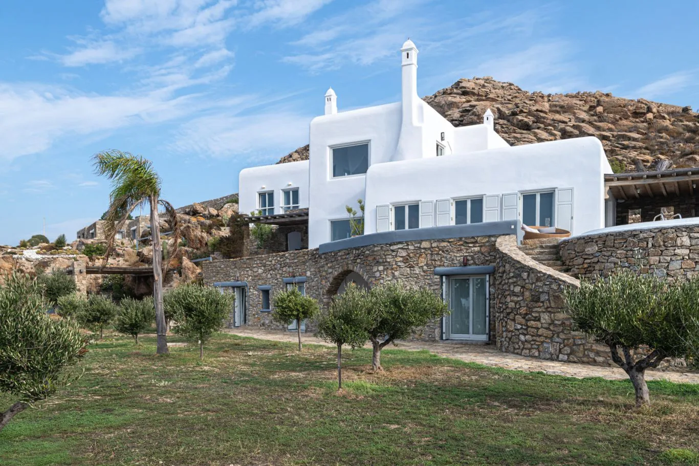 White buildings with stone walls stand in a dry, rocky landscape.